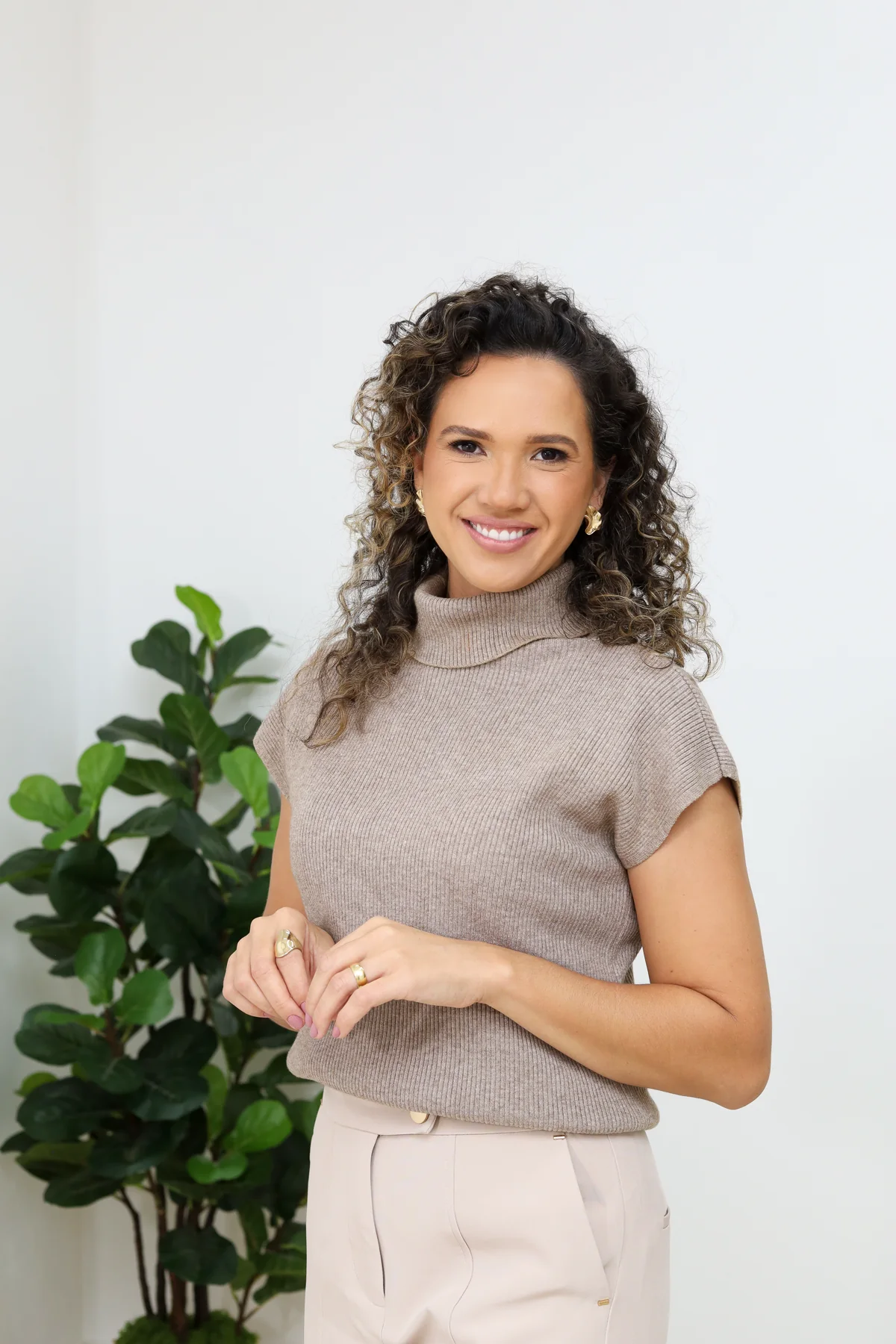 Mari Cordeiro sorrindo ao lado de uma planta